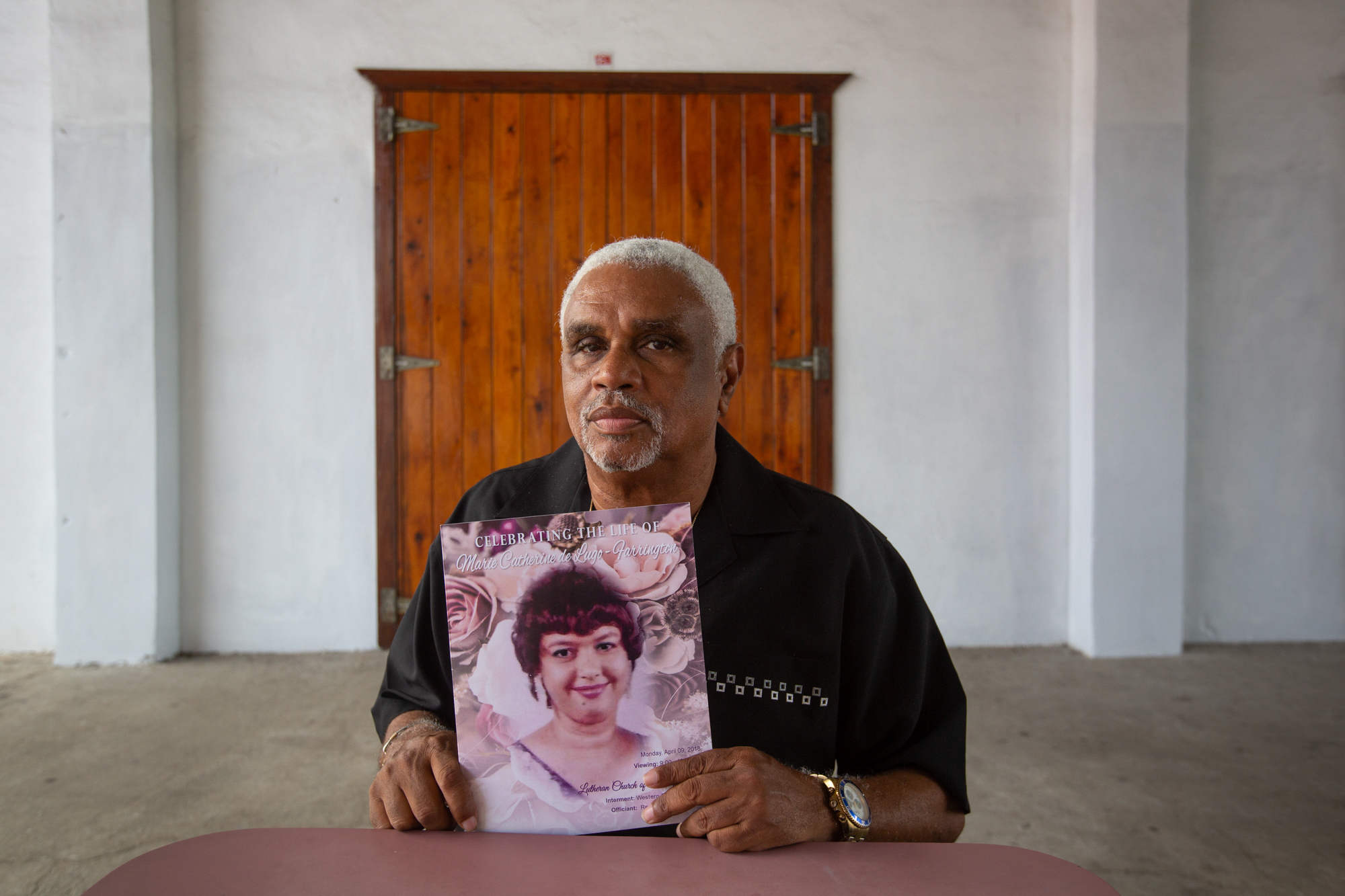 Michael Farrington - Michael Farrington of St. Thomas, U.S. Virgin Islands, holds a copy of his wife's funeral program. Marie Catherine de Lugo-Farrington was medically evacuated to Puerto Rico before Hurricane Irma, then evacuated to the mainland before Hurricane Maria hit Puerto Rico. She died shortly after Farrington brought her home to St. Thomas. He says FEMA did a poor job of tracking patients who were medically evacuated. (Anya Magnuson/News21)
