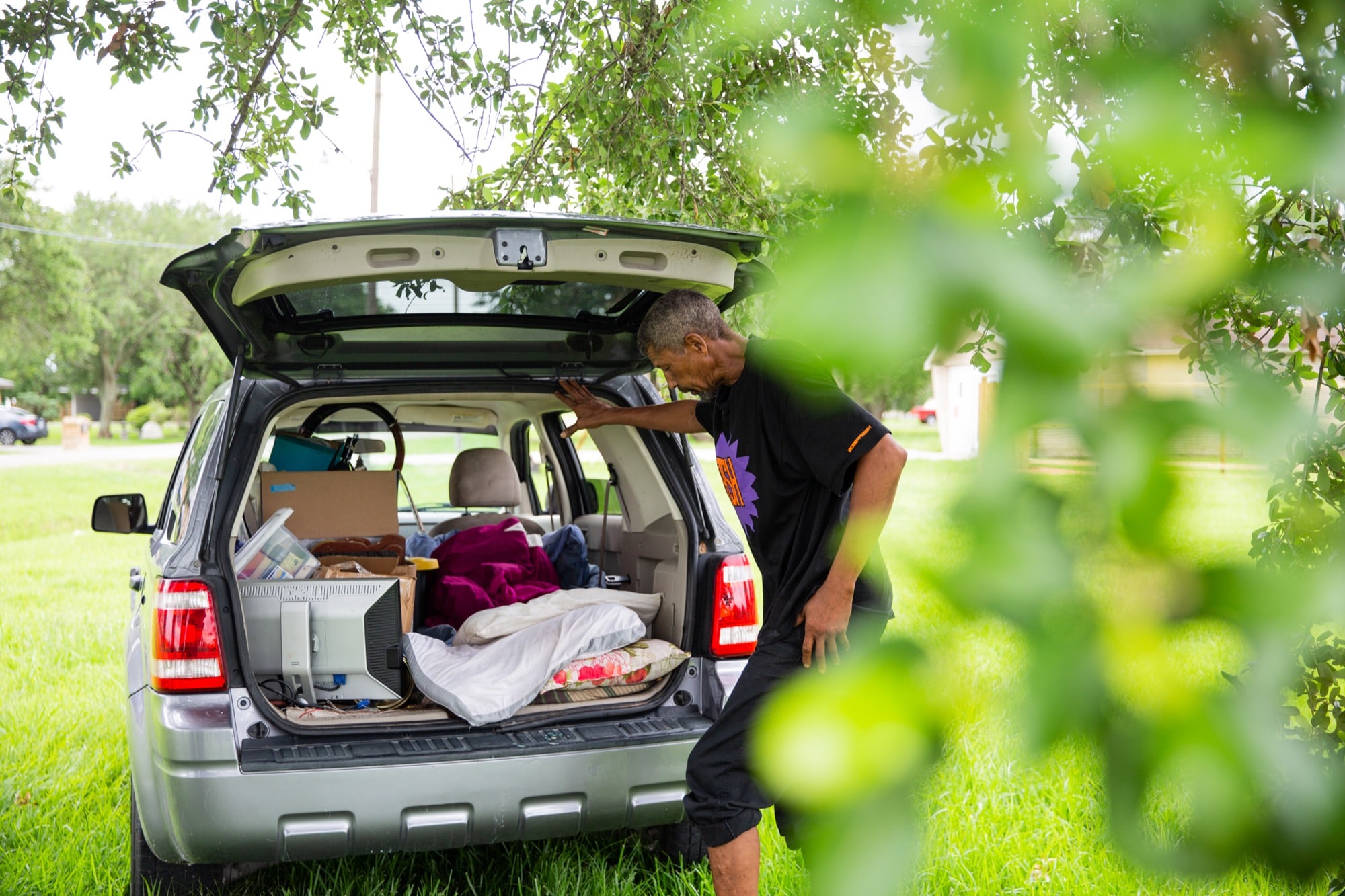 Benjamin Davis, who’s at least 6-foot tall, sleeps in a borrowed car that also holds his remaining possessions.  He moves all of his belongings to one side and lays down comforters and pillows to make the spot between the trunk and back seat more comfortable. (Stacy Fernández/News21)