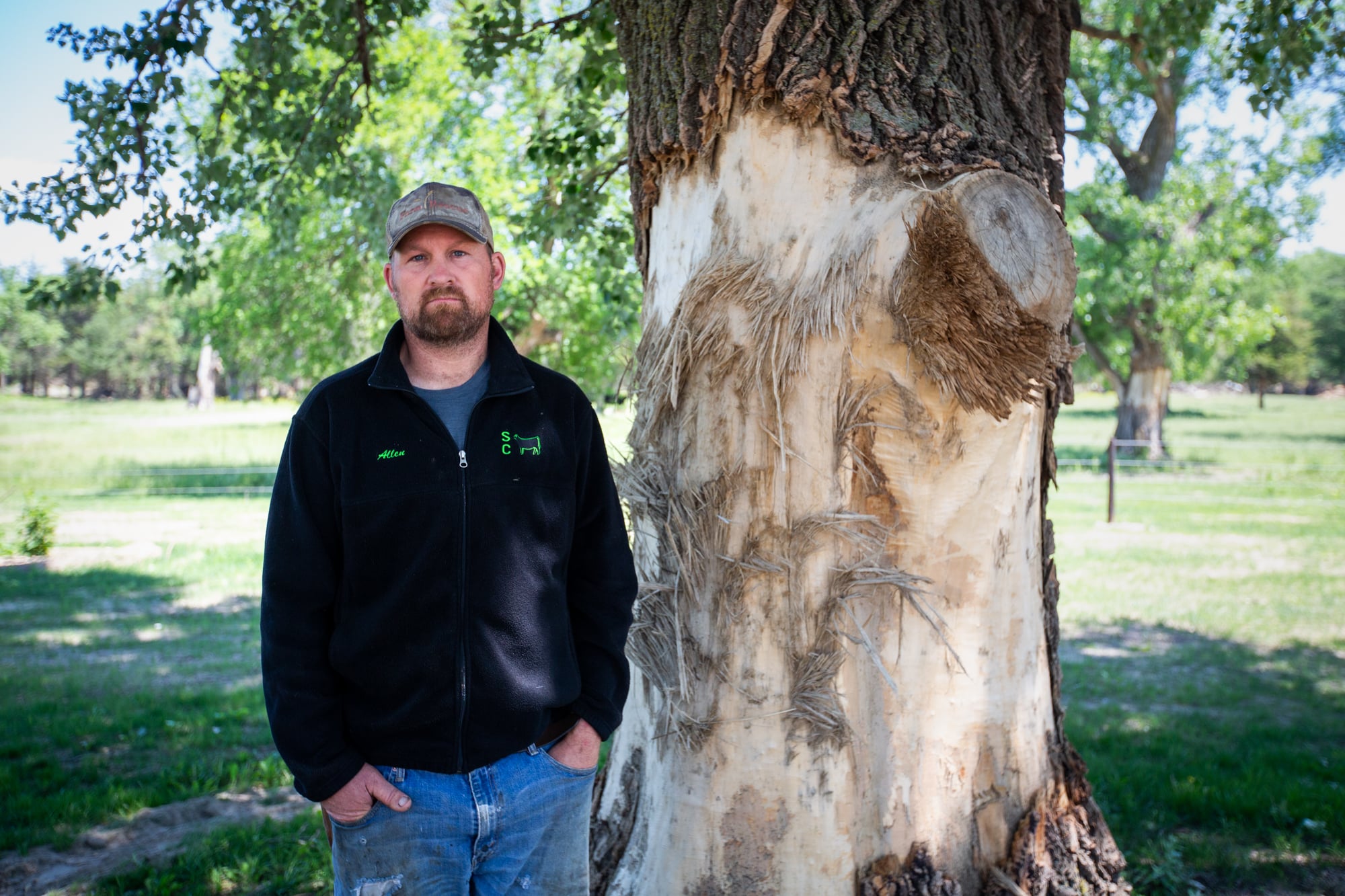 Anthony Ruzicka stands next to a tree on his Nebraska property whose trunk shows at least 6 feet of damage from large ice chunks that flooded the property last spring. In addition to many outbuildings, the Ruzickas lost their home. (Anya Magnuson/News21)