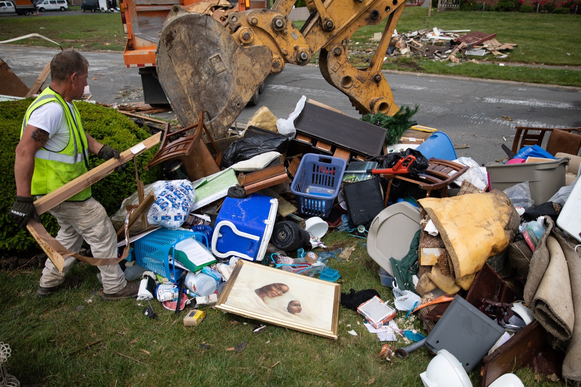 Phil Sloan, a worker from adjacent Butler County, Ohio, sorts through ruined belongings that Dayton residents have set out for removal. “I just feel bad. That’s a lifetime of stuff laying out here in a pile,” Sloan said.  (Stacy Fernández/News21)